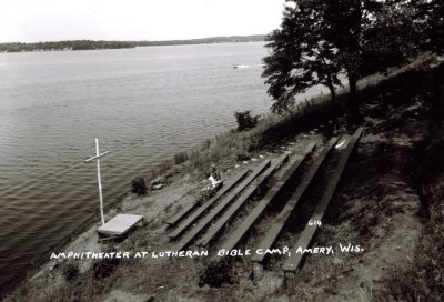 Outdoor church pews by the lake with a large cross